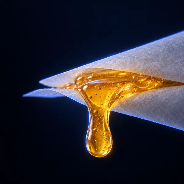 Gota de live rosin ámbar que cae entre dos hojas de papel de horno