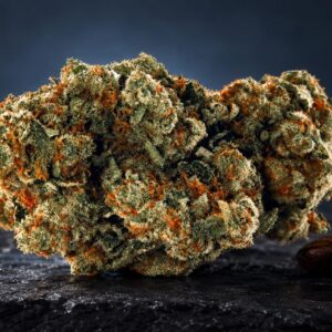 Flores de Tangie weed con tonos dorados, verdes y naranjas sobre superficie oscura, junto a granos de café